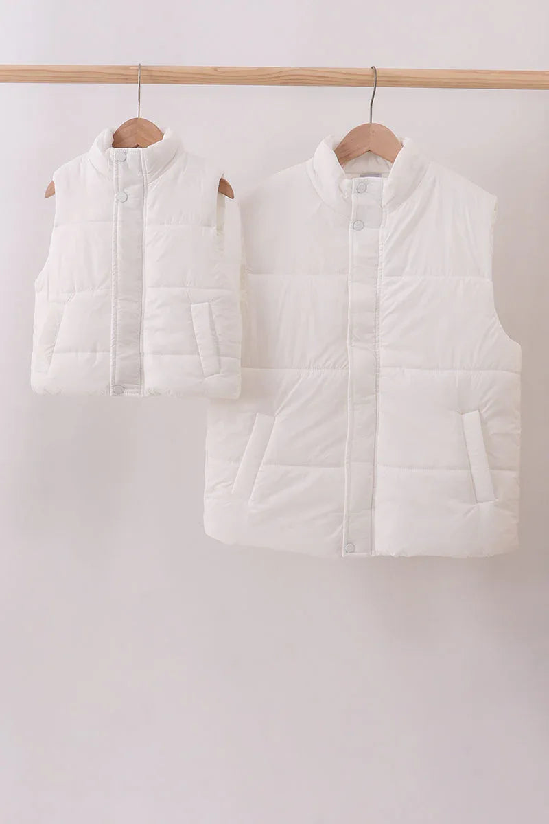 Two white puffer vests hanging on wooden hangers against a white background