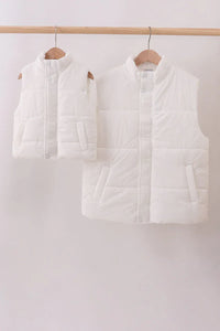 Two white puffer vests hanging on wooden hangers against a white background
